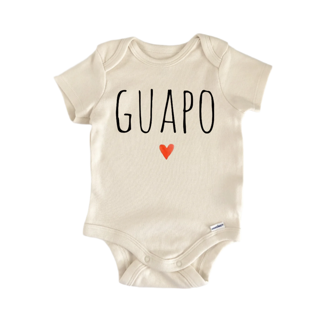 A beige baby onesie with the word "GUAPO" printed on it, along with a small red heart symbol.