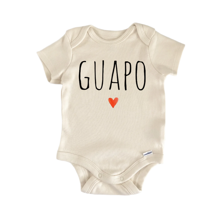 A beige baby onesie with the word "GUAPO" printed on it, along with a small red heart symbol.