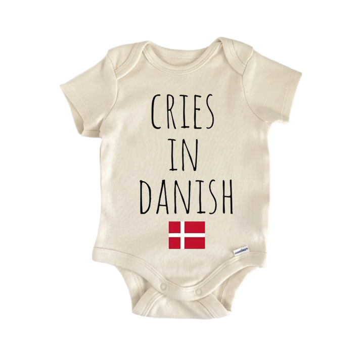 A beige baby onesie with the text "CRIES IN DANISH" printed on it, along with a small red flag below the text.