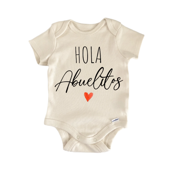 A beige baby onesie with the text "Hola Abuelos" printed on it, along with a small red heart symbol.
