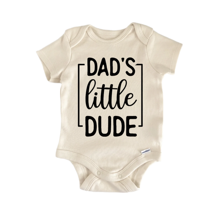 A beige baby onesie with the text "DAD'S LITTLE DUDE" printed on it.