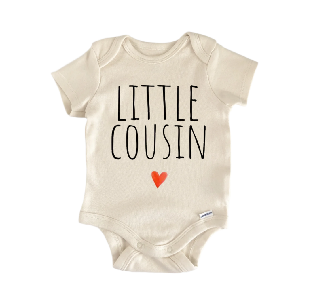 A beige baby onesie with the text "LITTLE COUSIN" printed on it, along with a small red heart symbol.