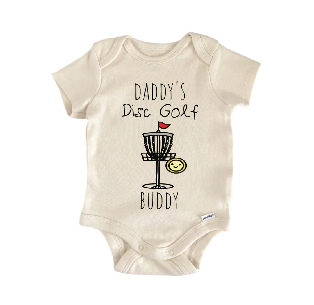 A beige baby onesie with a graphic design depicting a frisbee golf basket and the text "DADMY'S Disc Golf BUDDY" printed on it.