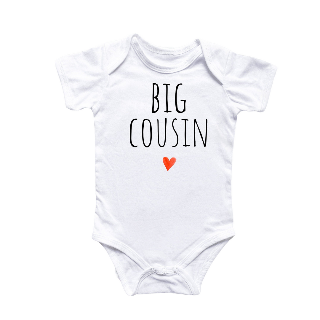 a white baby bodysuit with the words big cousin on it