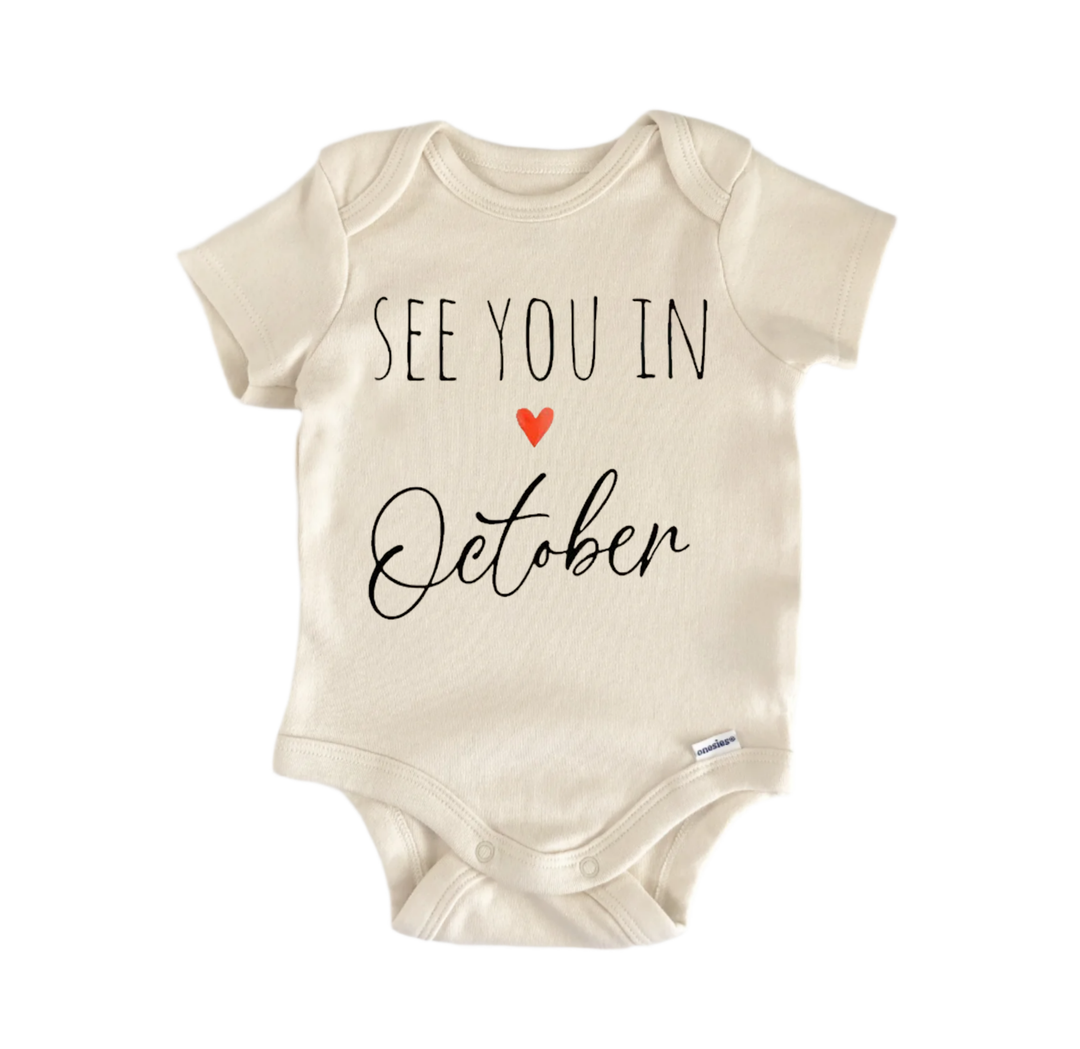 A beige baby onesie with the text "See you in October" printed on it.