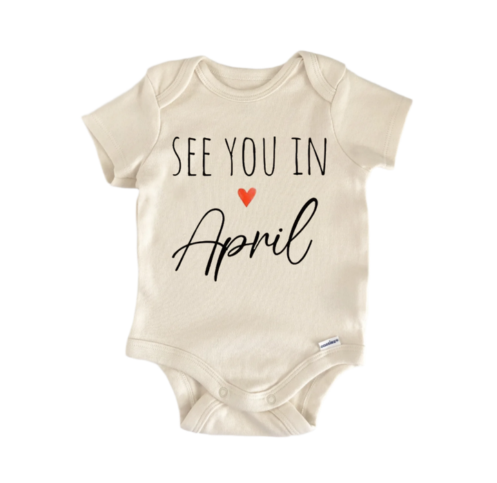 A beige baby onesie with the text "See you in April" printed on it.