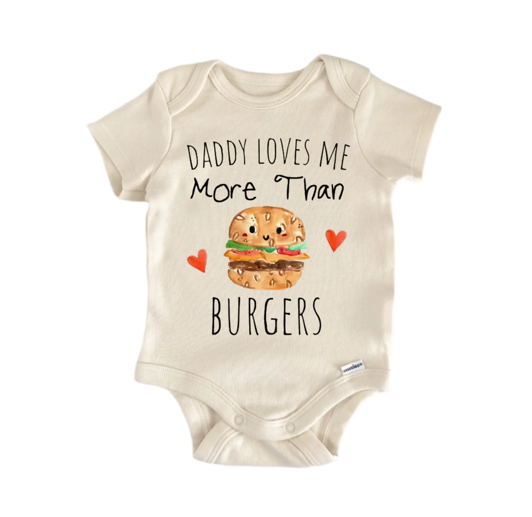 A baby onesie with a printed message that reads "DADMY LOVES ME MORE THAN BURGERS" along with an illustration of a hamburger.