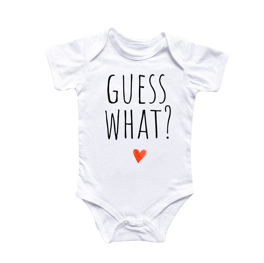 a white bodysuit with the words guess what on it