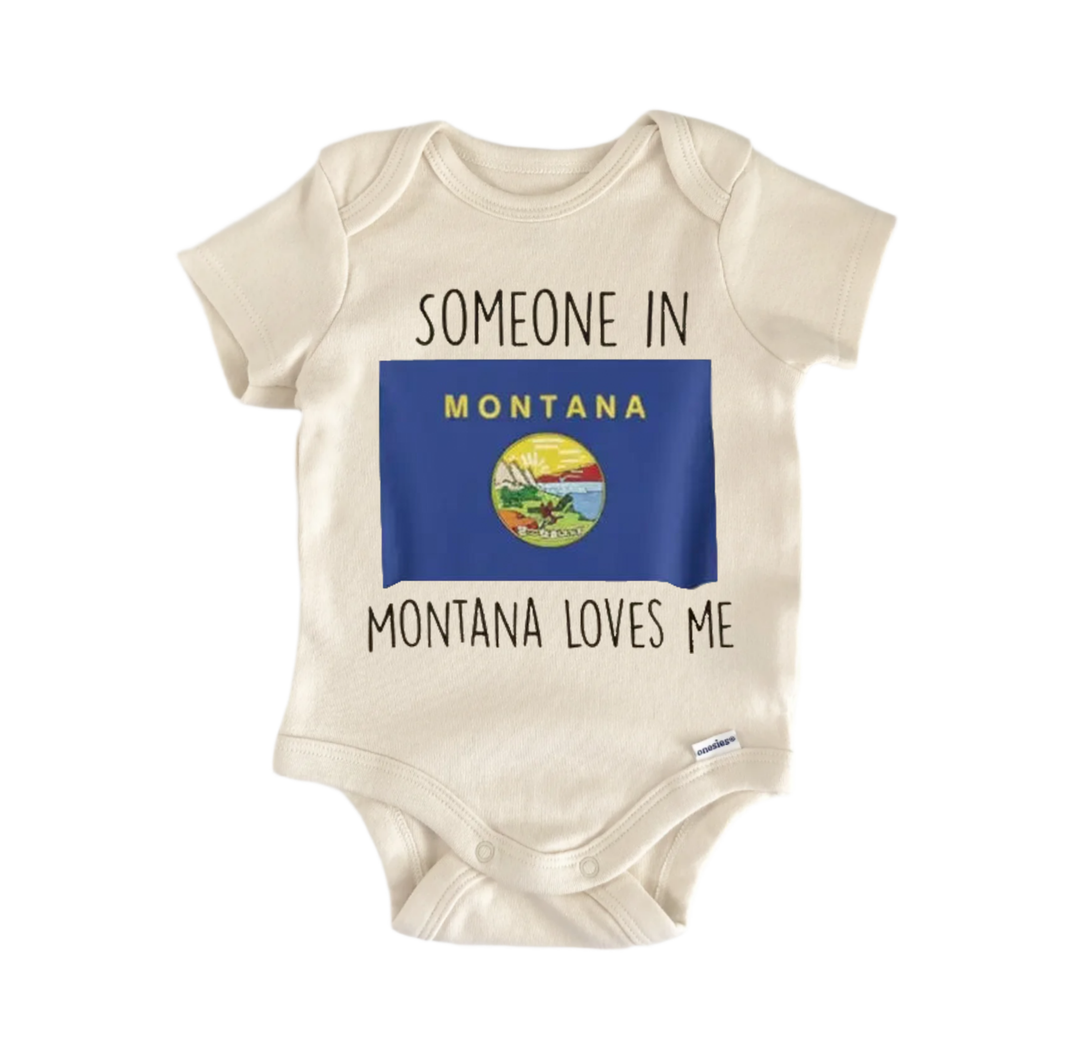 A beige baby onesie with the text "SOMEONE IN MONTANA MONTANA LOVES ME" printed on it, along with a small Montana state flag.
