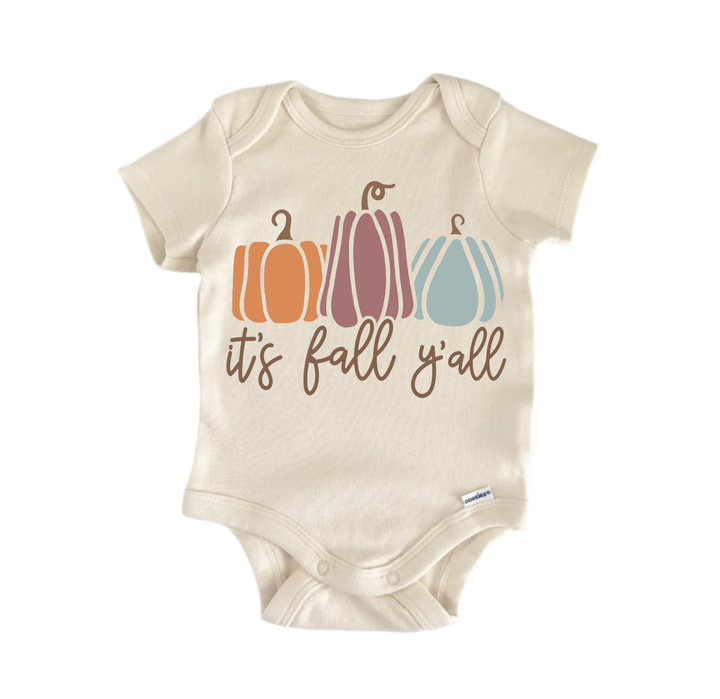 A beige baby onesie with a graphic design featuring three pumpkins in different colors and the text "it's fall y'all" printed on it.