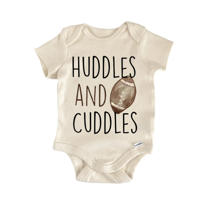 A beige baby onesie with the text "Huddles and Cuddles" printed on it, along with an image of a football.