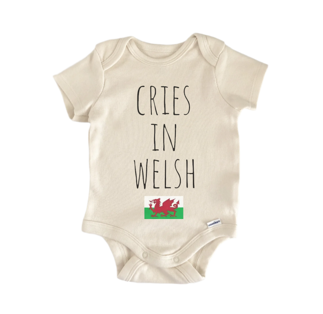 A beige baby onesie with the text "CRIES IN WELSH" printed on it, along with a small Welsh flag below the text.