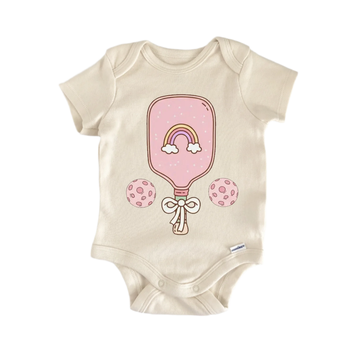 A beige baby onesie with a pink paddle and two polka dot circles on it.