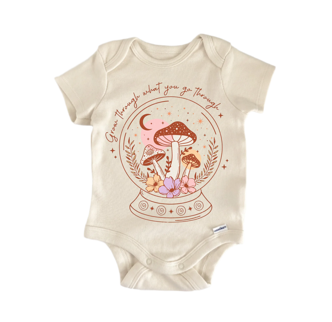 A beige baby onesie with a mushroom and flower design on it, along with the text "Go through what you go through" printed on the front.