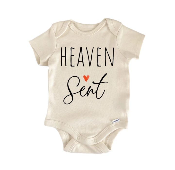 A beige baby onesie with the text "HEAVEN Sent" printed on it.