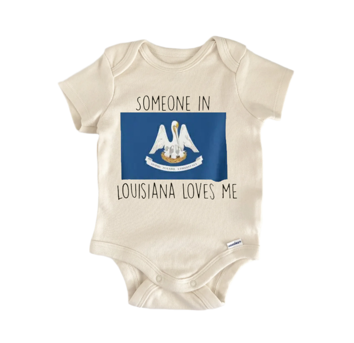 A beige baby onesie with a blue Louisiana state flag design and the text "SOMEONE IN LOUISIANA LOVES ME" printed on it.