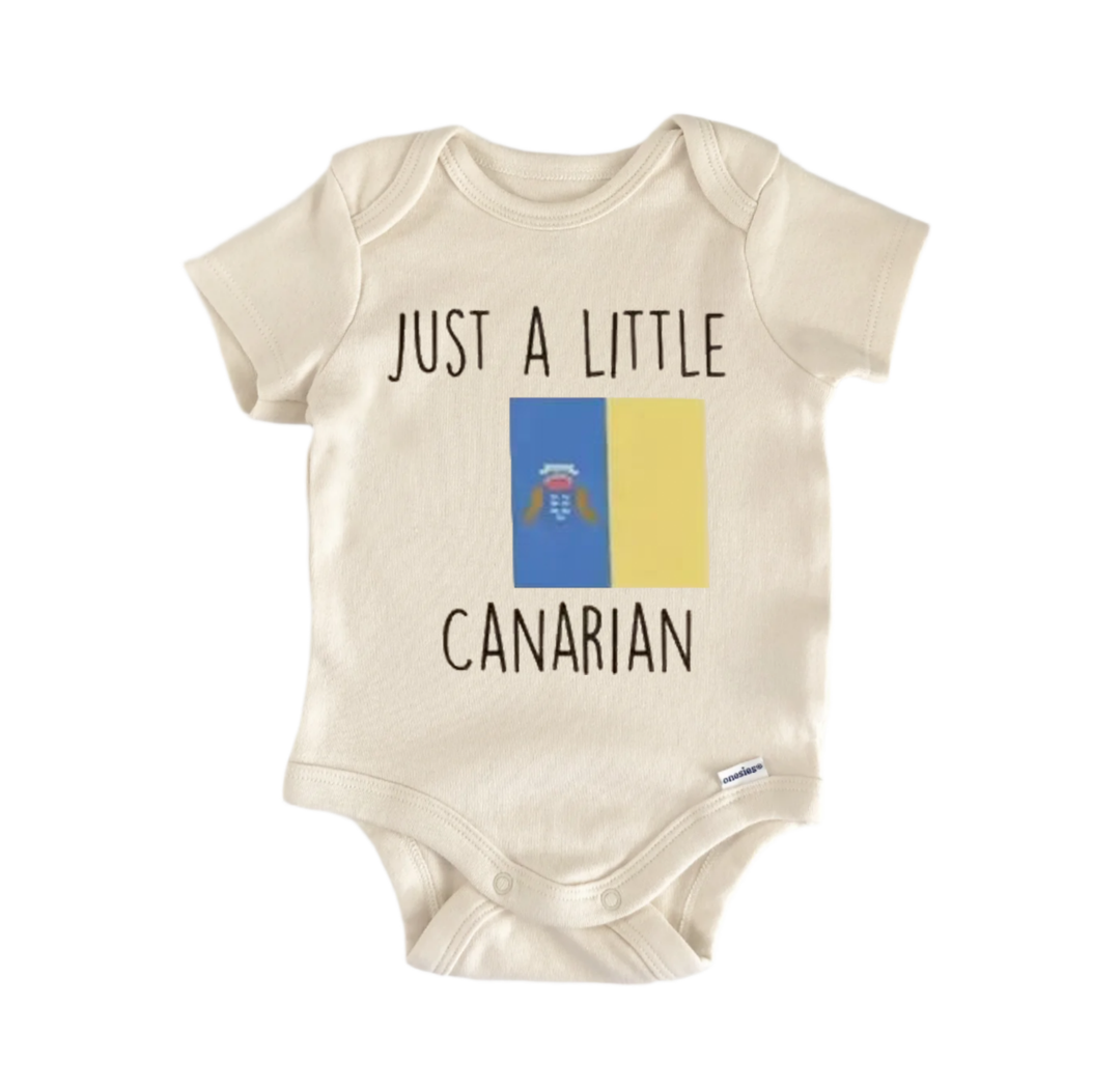 A beige baby onesie with the text "JUST A LITTLE CANARIAN" printed on it, along with a small flag design.