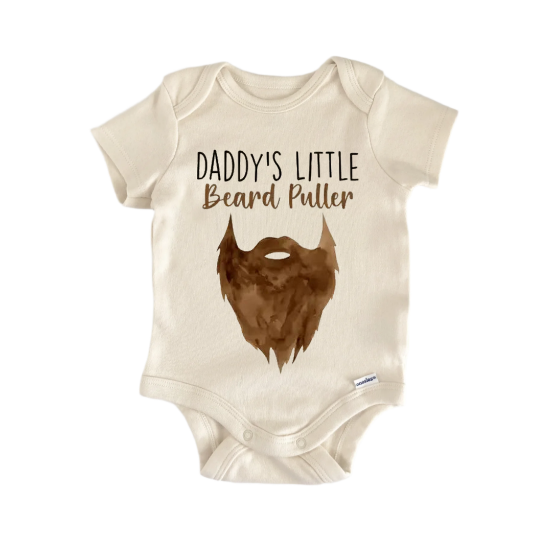 A beige baby onesie with a brown beard printed on it, along with the text "DADDA'S LITTLE Beard Puller" printed above the beard.