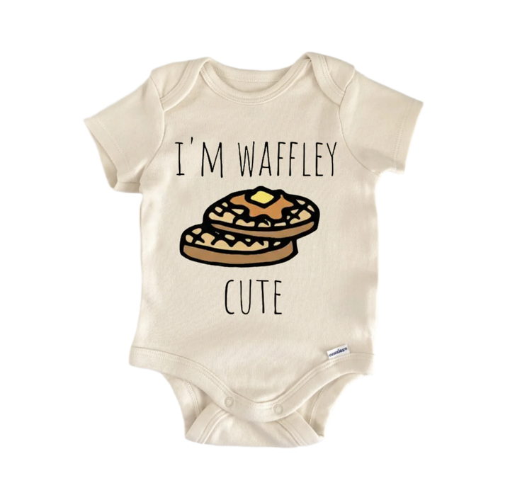A beige baby onesie with a printed design of two waffles and the text "I'M WAFFLEY CUTE" printed on it.
