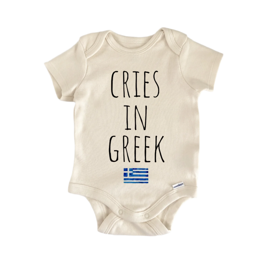 A beige baby onesie with the text "CRIES IN GREK" printed on it, along with a small Greek flag below the text.