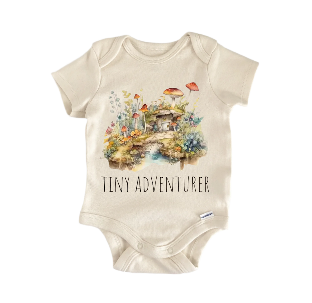 A baby onesie with a printed design of a forest scene and mushrooms, along with the text "Tiny Adventurer" printed on it.