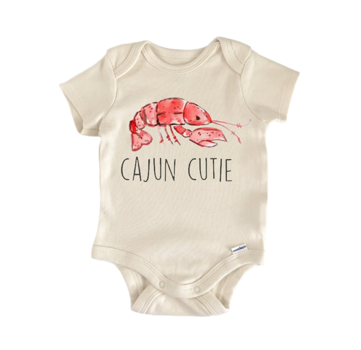 A beige baby onesie with a red lobster printed on it and the text "CAJUN CUTIE" printed below.