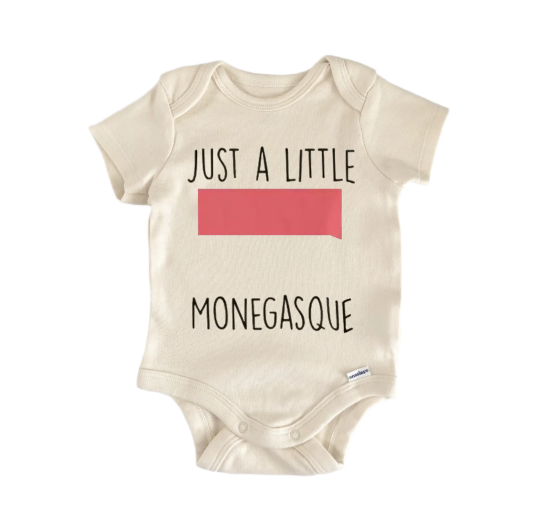 A beige baby onesie with the text "JUST A LITTLE MONEGASQUE" printed on it.