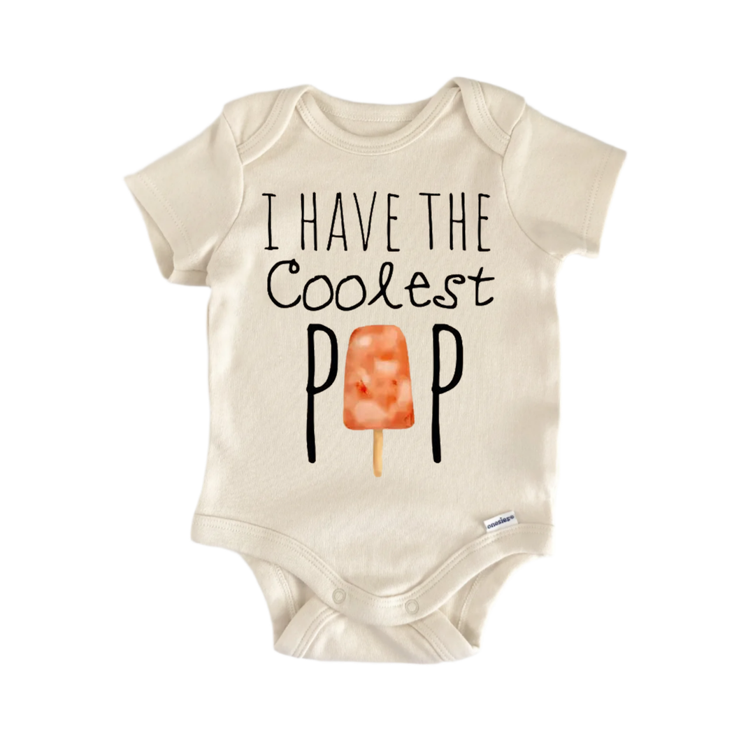 A beige baby onesie with the text "I HAVE THE COOLEST POP" printed on it, along with an illustration of an orange popsicle.