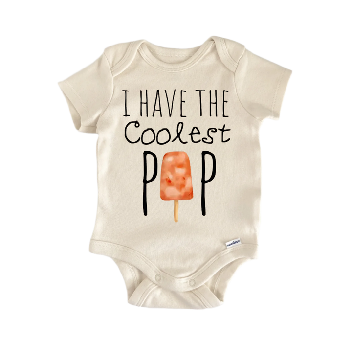 A beige baby onesie with the text "I HAVE THE COOLEST POP" printed on it, along with an illustration of an orange popsicle.